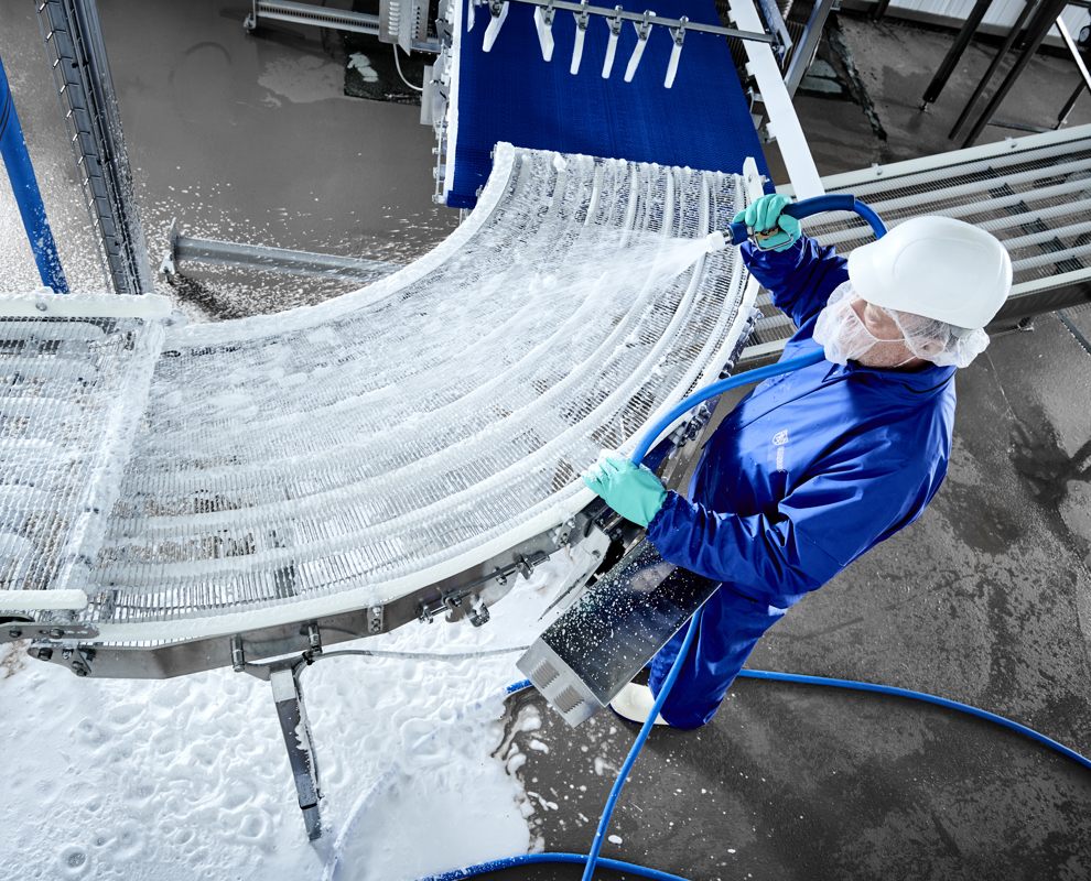 Operator using Foamico low pressure technology for conveyor cleaning